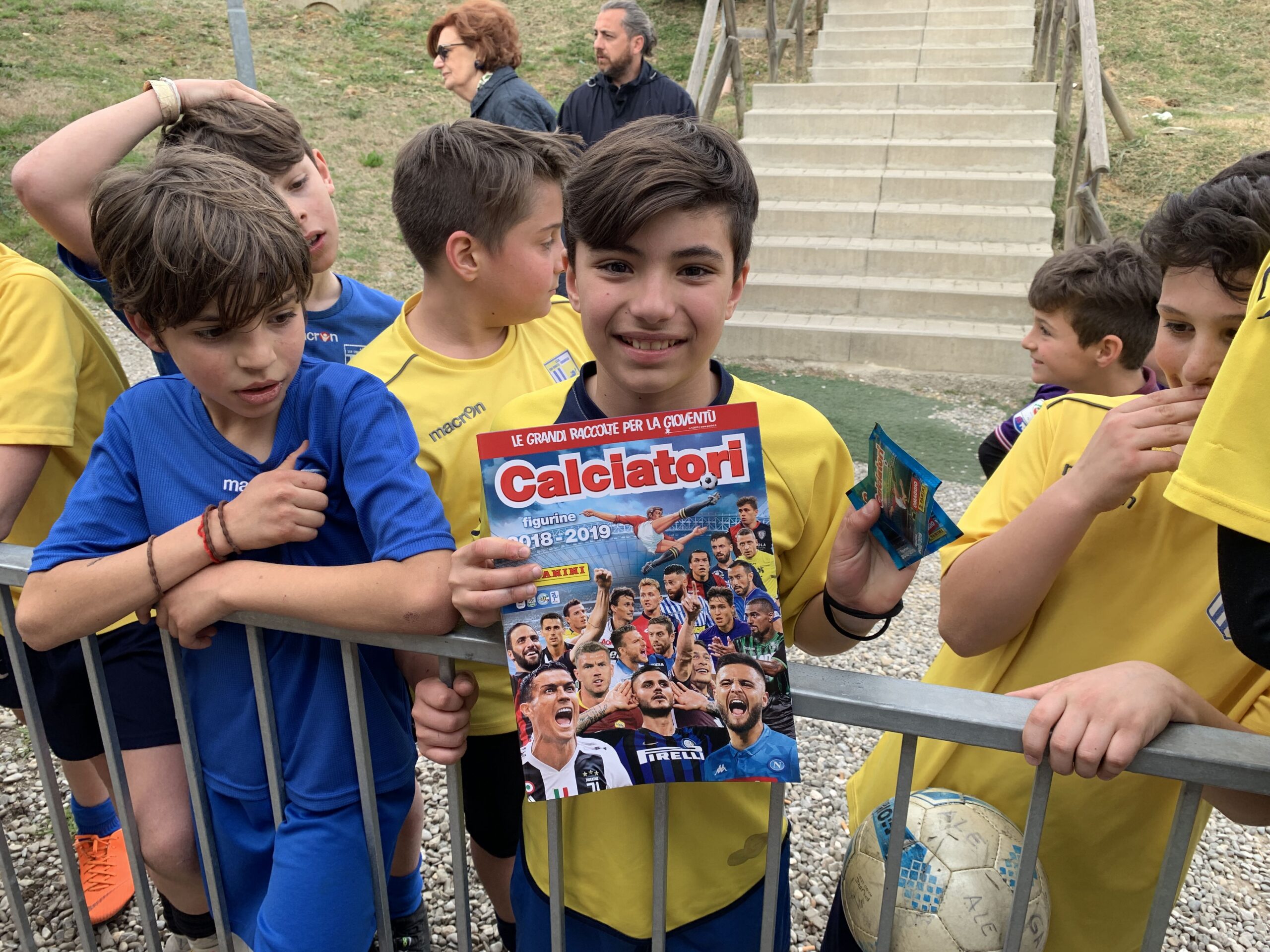 I giovani giallo blu in fila per ricevere album e figurine della
